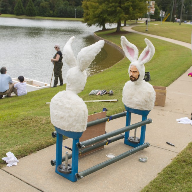 Crews install A water feature sculpture of two men in bunny suits