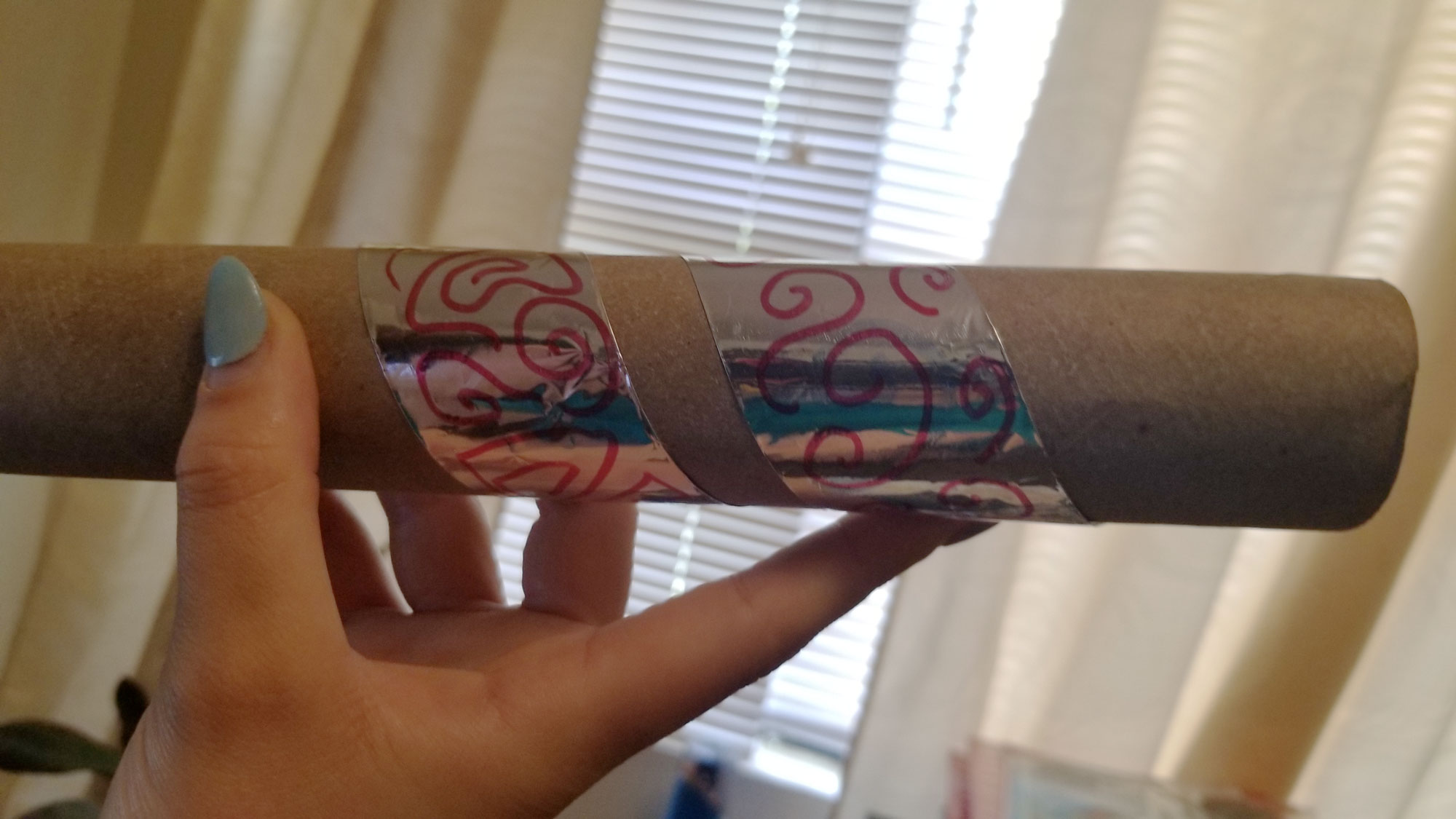 Decorated aluminum foil wrapped around an empty paper towel roll.