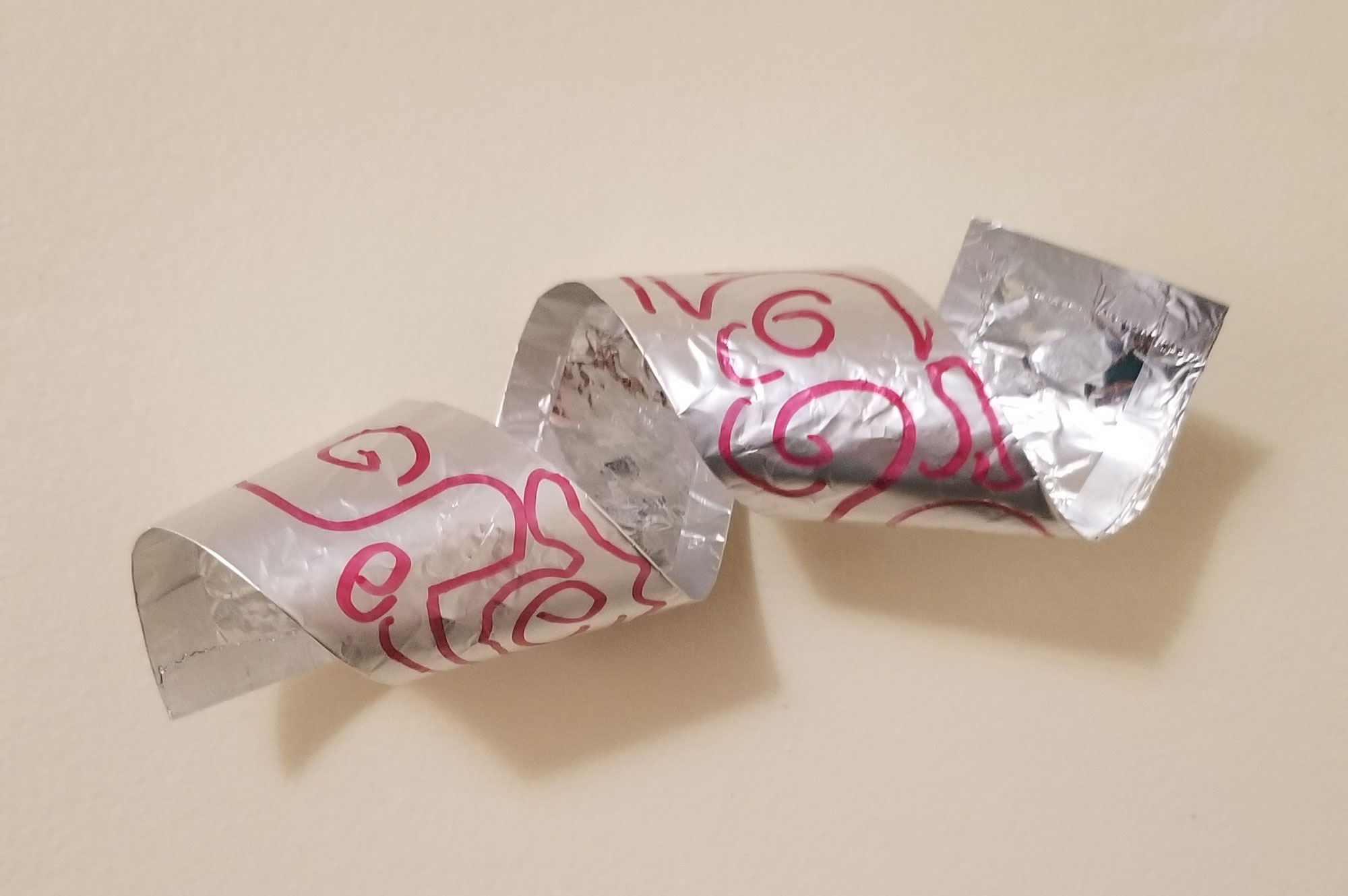 A coil of aluminum foil decorated as an art project for children.