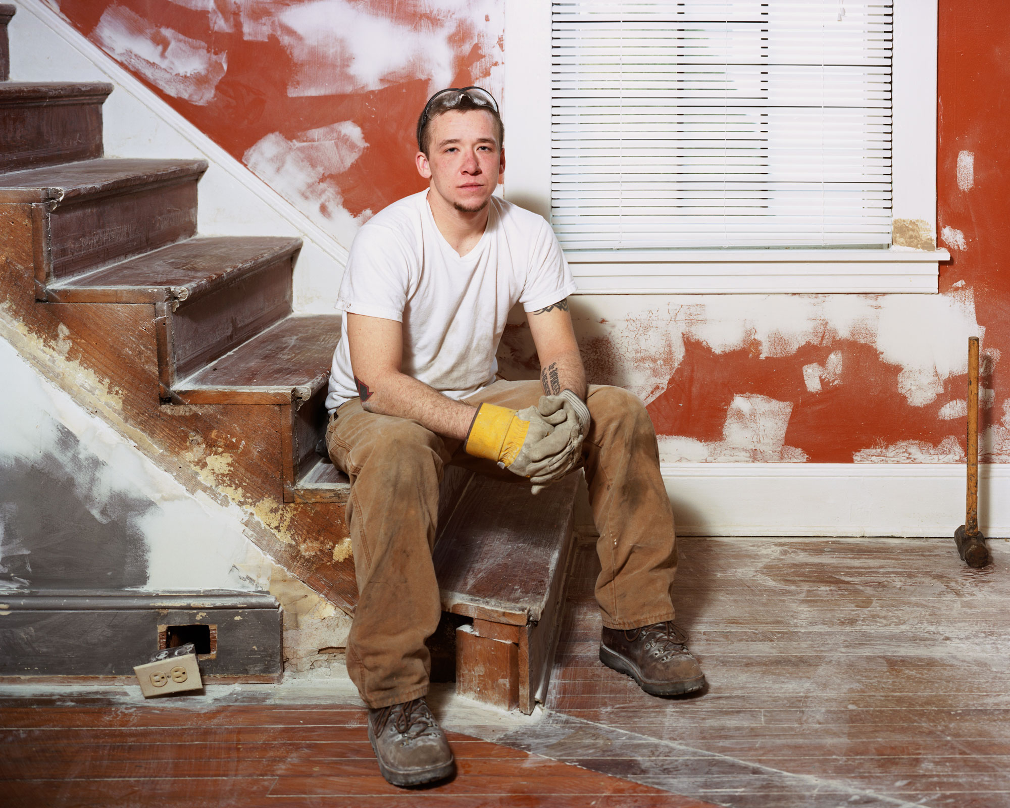 A construction worker sits on unfinished stairs.