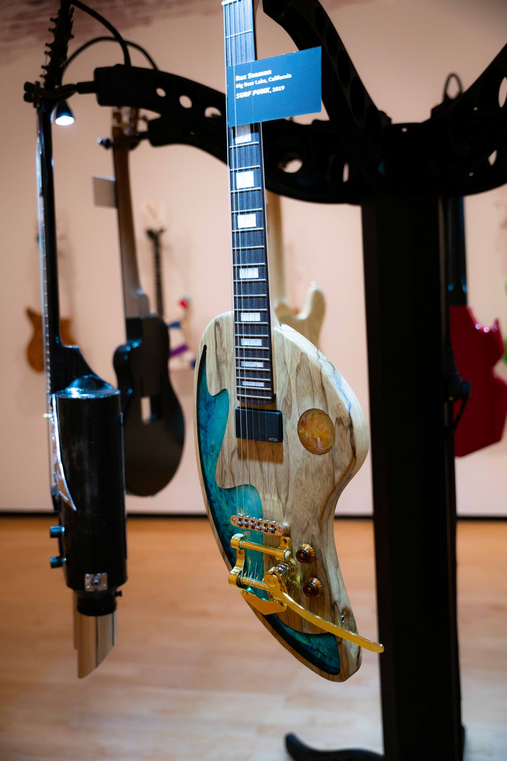 A wooden electric guitar shaped like a painters palette with gold and blue accents