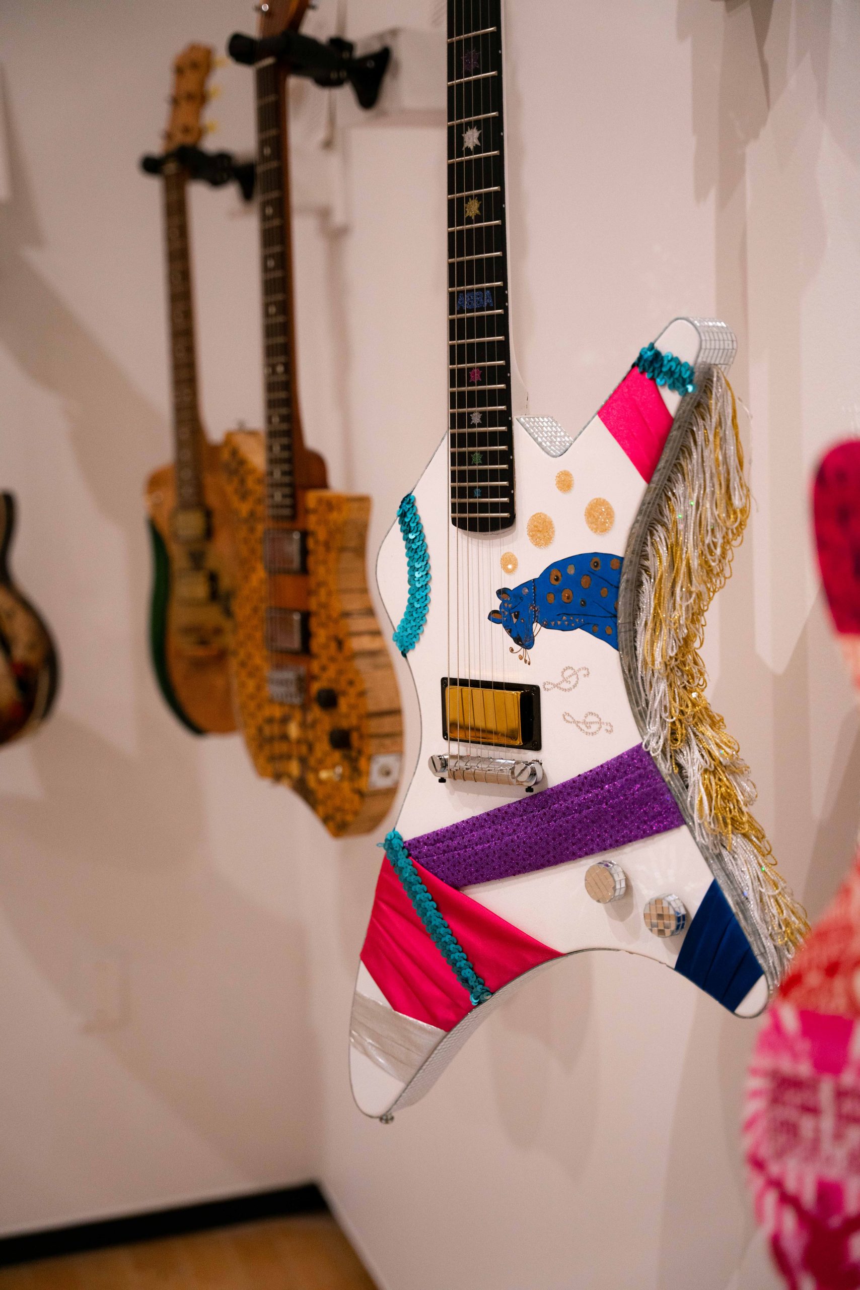 A colorful electric guitar decorated with bright fabric and tassels