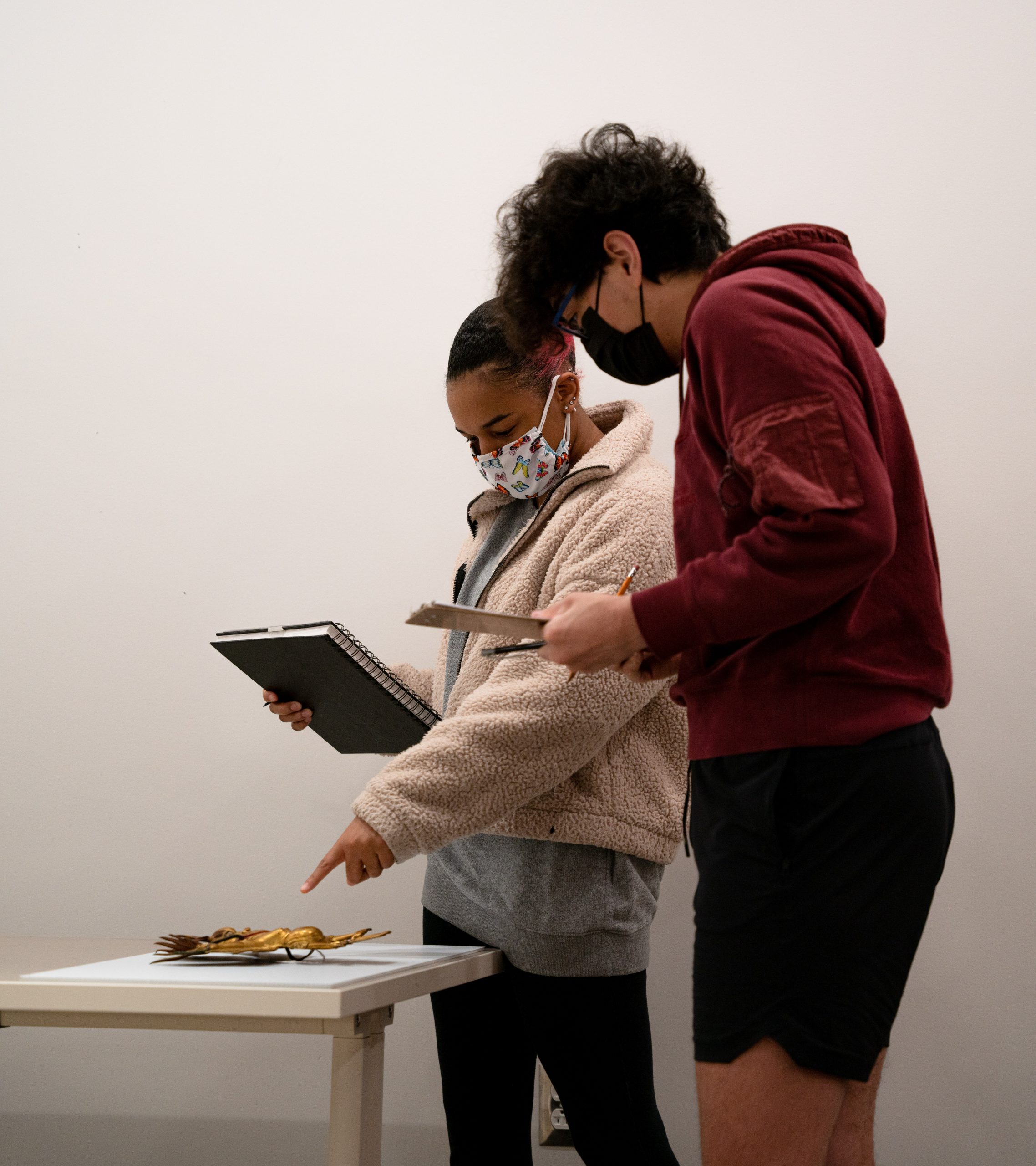 Two students pointing and discussing a bronze statue.
