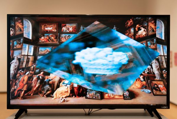 A tv screen displays a rotating cube surrounded by renaissance artwork. ren
