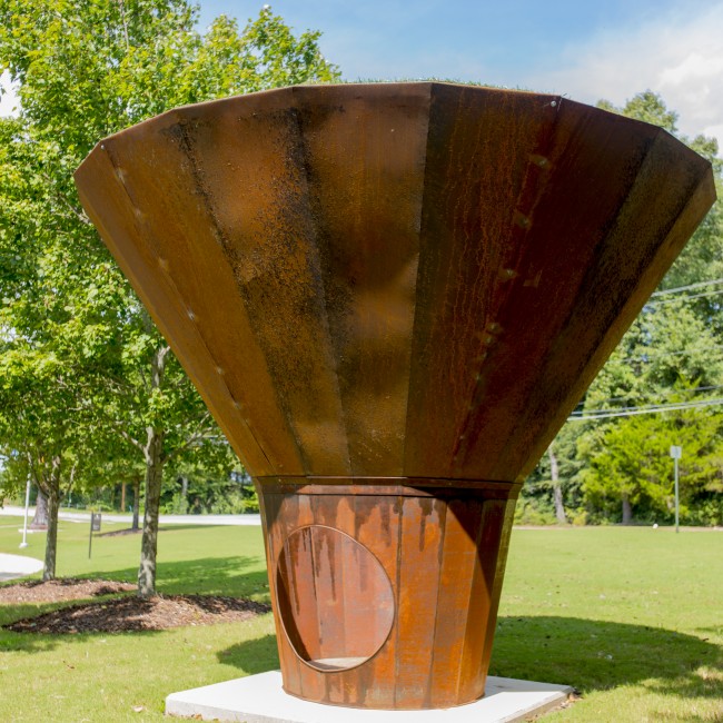 A steel scuplture in the shape of a cone, with a small opening at the base
