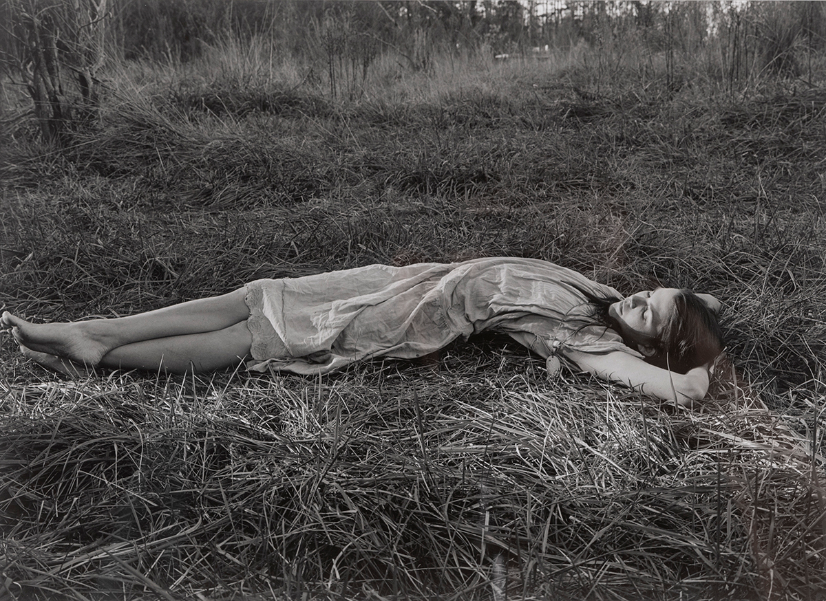 A photograph of a woman lying in the grass.