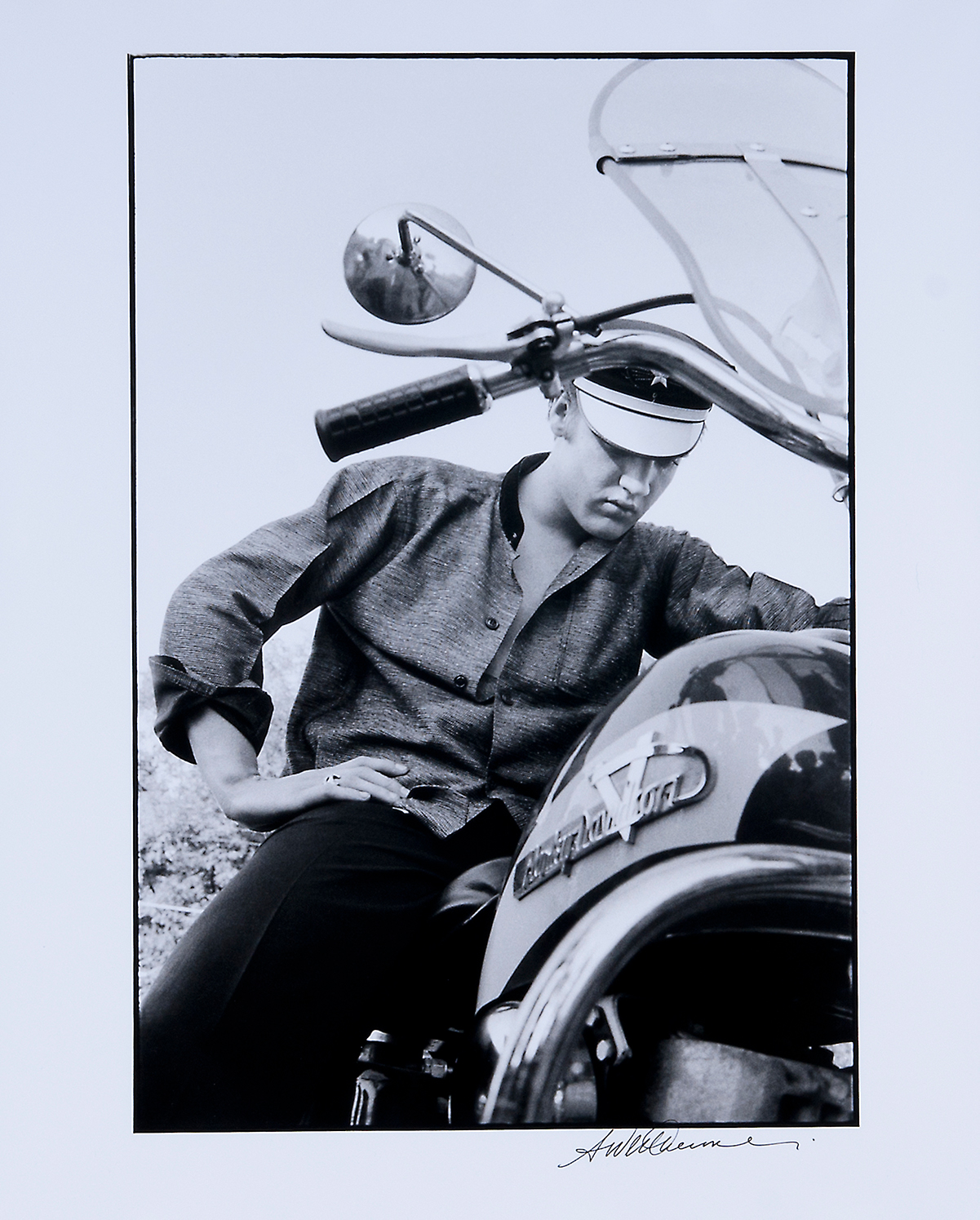 Musician Elvis Presley sits on a motorcycle.