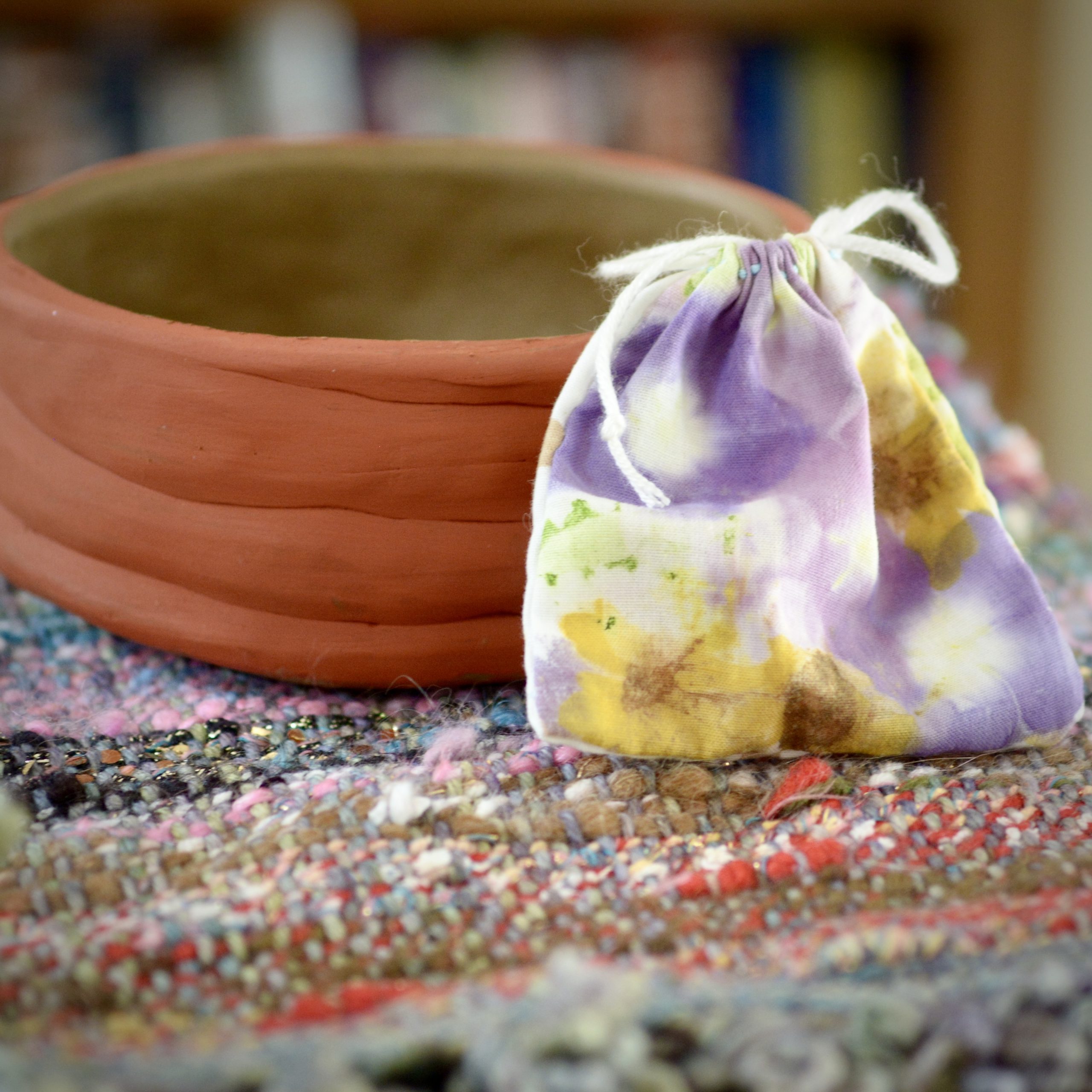 A small bag placed against a handmade coiled pot.
