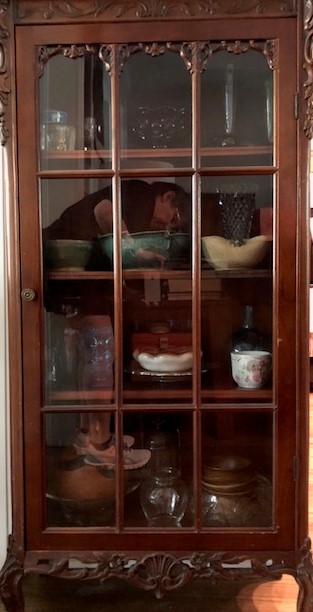 A wooden china cabinet filled with delicate teacups.