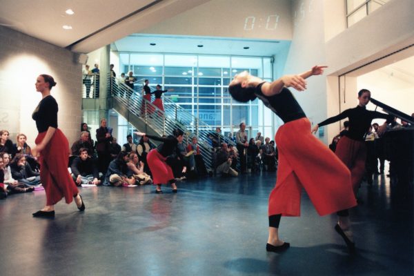 A dance performance with viewers surrounding in a lobby of a building