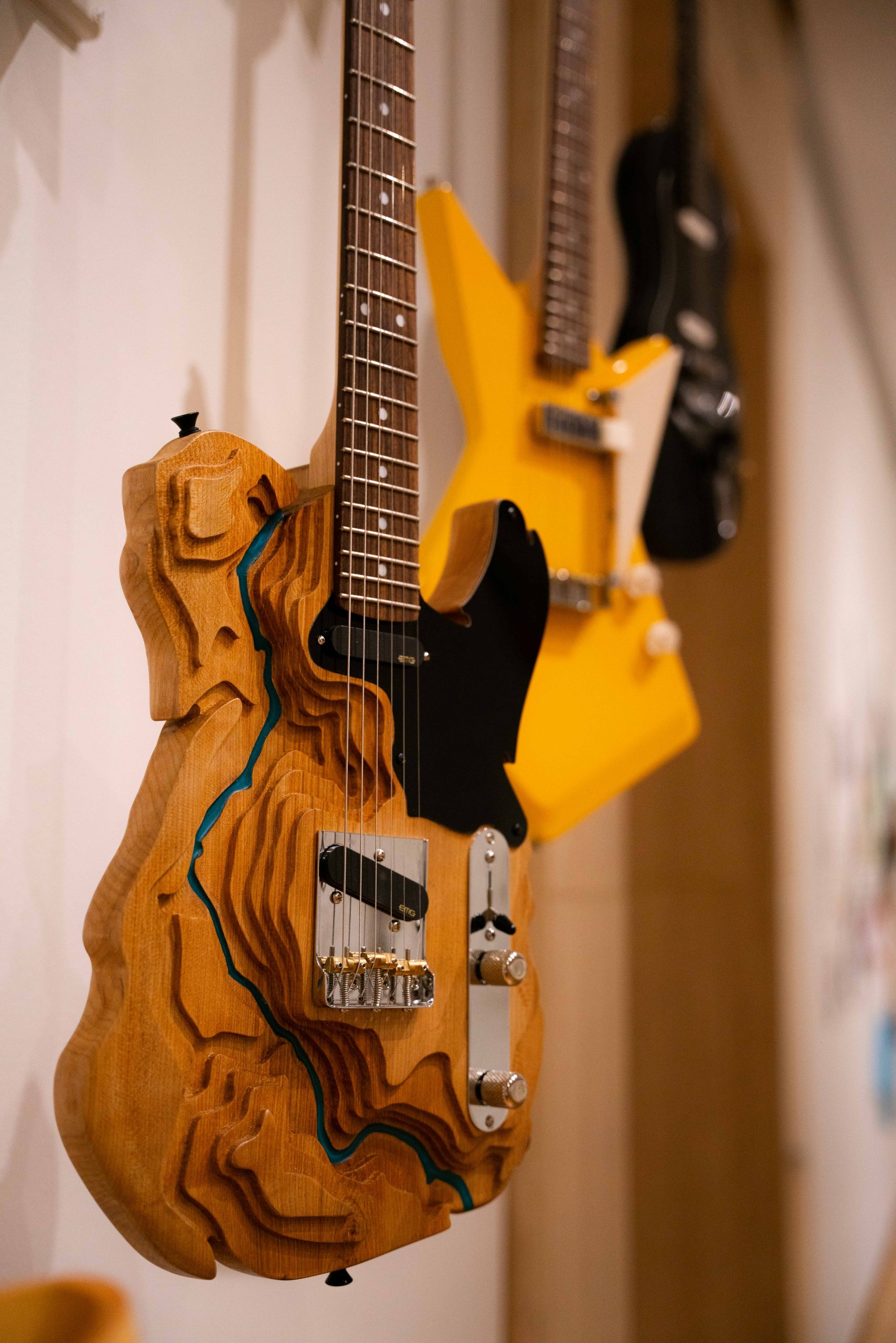 A wooden electric guitar carved to look like a topographical map of a river