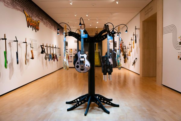 A circular stand holds multiple guitars in the center of a gallery.