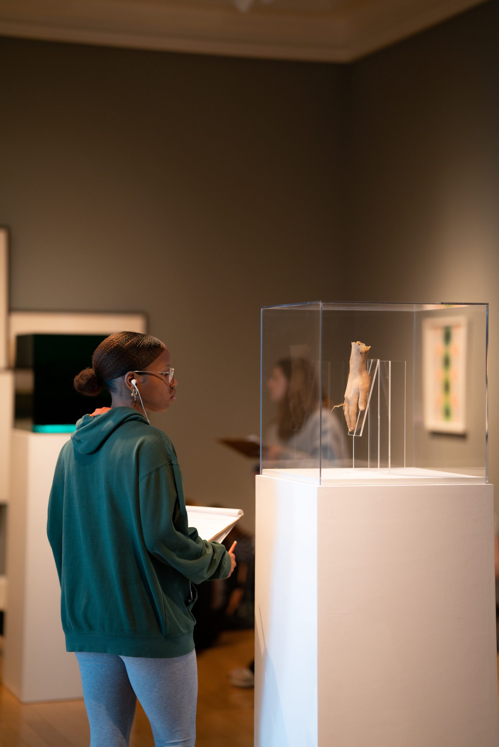 A student looks at a sculpture of a disembodied hand