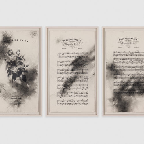 Three pieces of framed sheet music with large, dusty smudges of graphite and charcoal.