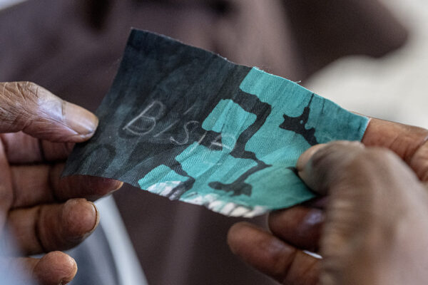 Hands hold a teal and black patterned fabric with a name stitched into it.