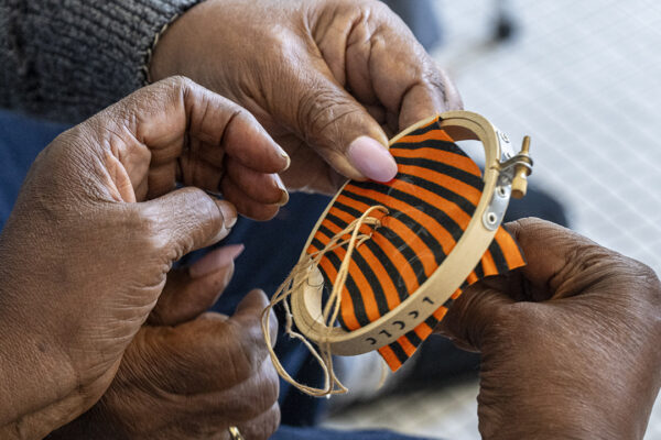 Hands hold a cross stitch hoop and stitch fabric.