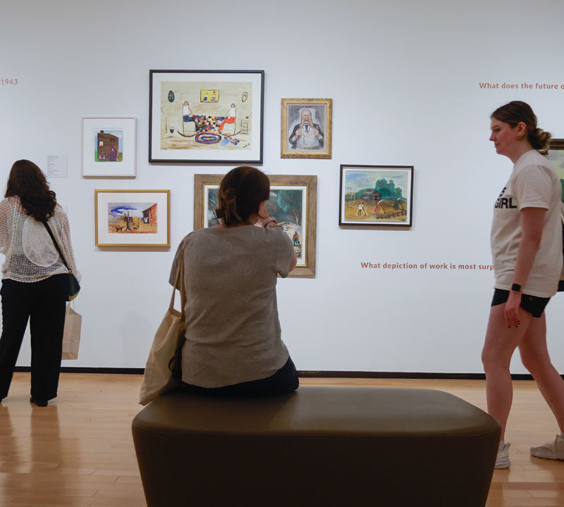 Four people view art in a gallery.