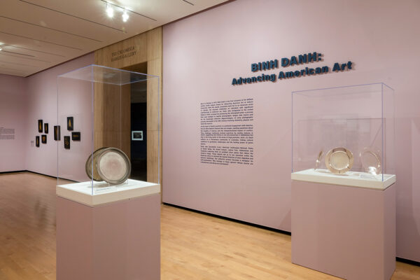 Display cases with silver plate artworks and wall text for the exhibition, "Binh. Danh: Advancing American Art."