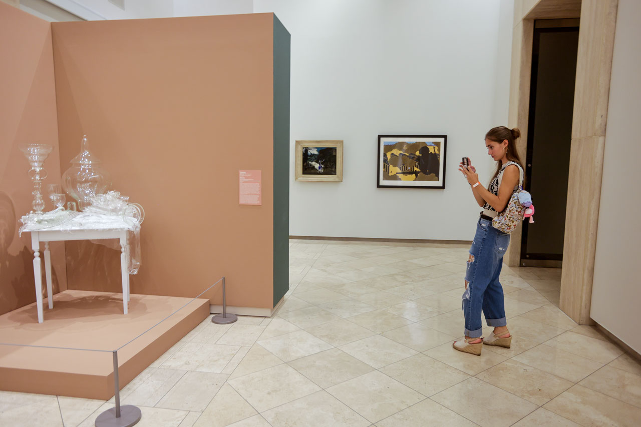 A person takes a photo with their cellphone of a glass sculpture.