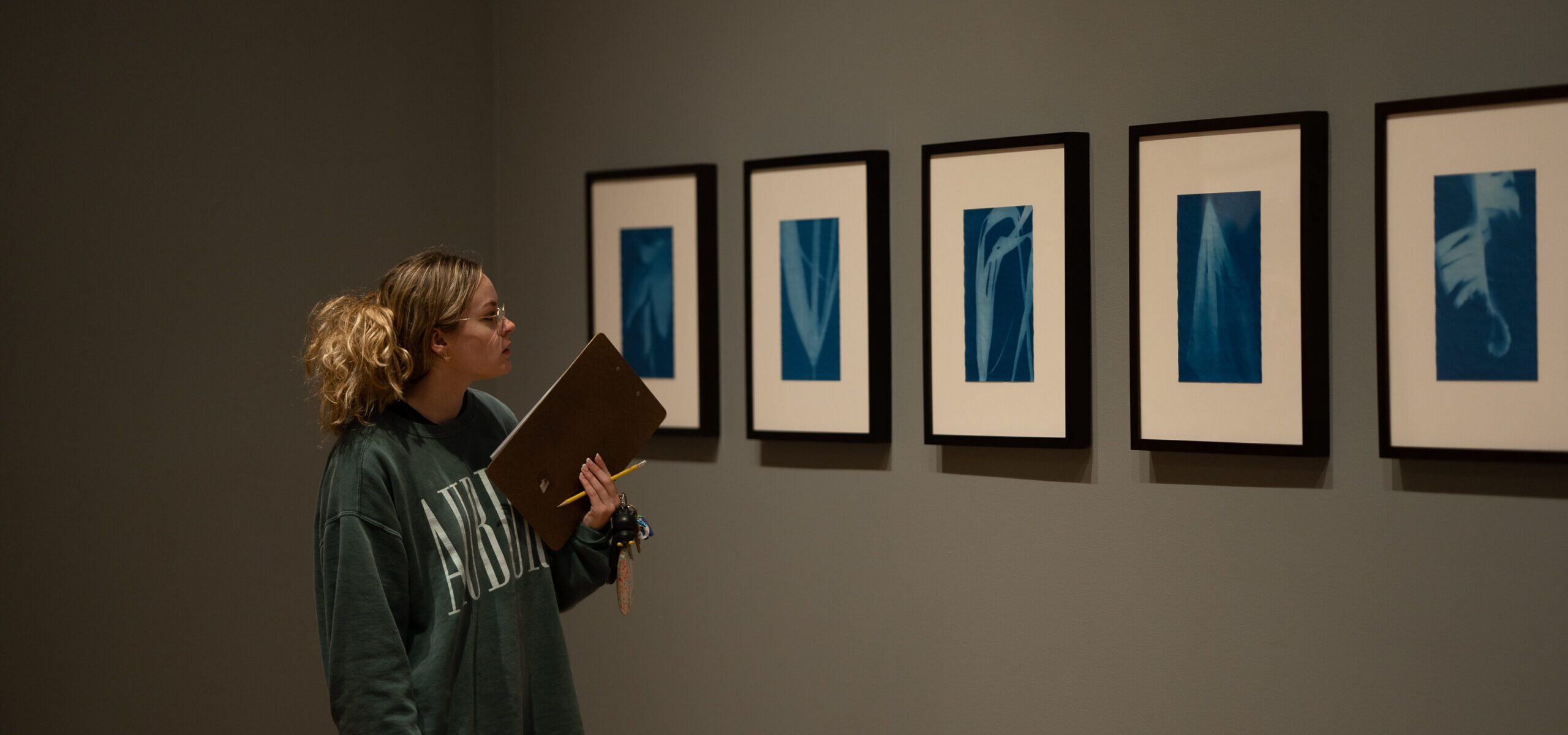2022_11-17 Manon with Class-12 A student looks at a grouping of 2D objects displayed on a gallery wall
