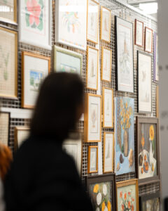 A figure stands in front of a wire rack filled with framed objects.