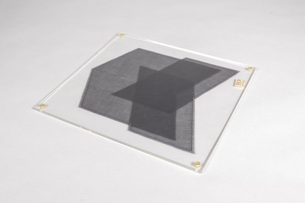 Three arrangements of grey fabric cut in geometric shapes sandwiched between two pieces of plexiglass