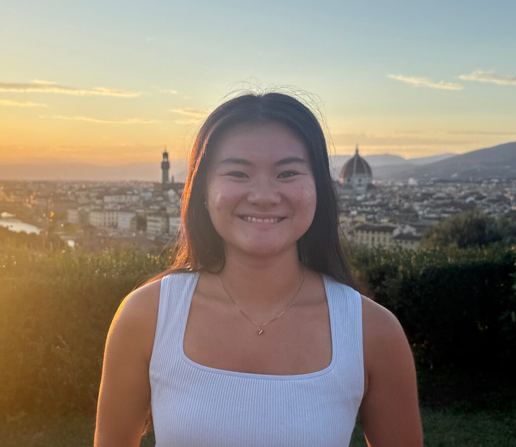 Lydia Rotta in Florence, Italy. Lydia has dark, long hair and wears a white tank top.